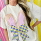 Person wearing a white t-shirt with a colorful Easter Bunny bow design against a multicolored striped background
