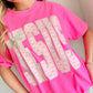 Woman wearing a pink t-shirt with decorative JESUS text with cross charm and graphics.