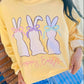 Person wearing a yellow sweatshirt with Easter bunny Hoppy Easter graphics and text.
