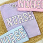 Three sweatshirts with 'NURSE' text in pastel colors with Peeps on a textured surface.