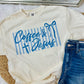 White t-shirt with 'Coffee & Jesus' text and blue stripes, paired with denim shorts on a light background.