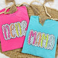 Two colorful t-shirts with 'New Mom' text on a textured surface.