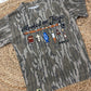 Camouflage t-shirt with fishing-themed Jesus design and text on a woven mat.