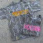 Two camouflage-patterned shirts with names 'Beckham' and 'Kolbie' on a concrete surface.