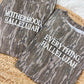 Two camouflage-patterned shirts with Motherhood, Hallelujah and Everything, Hallelujah puff text on a Bottomland surface