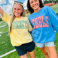 Two women standing on a football field wearing 'KENTUCKY' and 'REELS' shirts.