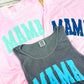 Three tank tops with 'MAMA' text in different colors on a pink background.