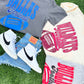Gray t-shirt with 'Dallas Football' text, white sneakers, and denim shorts on grass.