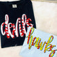 Black shirt with red and white text and light blue shirt with yellow and red text on a white surface.