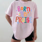 Person wearing a pink t-shirt with colorful text design on a plain background