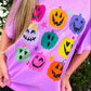 Person wearing a purple t-shirt with colorful pumpkin designs outdoors.