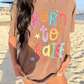 Woman wearing a brown t-shirt with 'Born to Praise' text on a beach