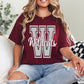 Person wearing a maroon t-shirt with 'Wildcats' printed on it, sitting on a checkered blanket.