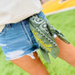 Person wearing denim shorts with a green bandana around their waist, featuring the word 'Hornets'.