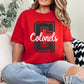 Person wearing a red 'Colonels' t-shirt sitting on a couch.