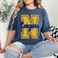 Woman wearing a blue t-shirt with 'N Cougars' design, sitting on a couch.